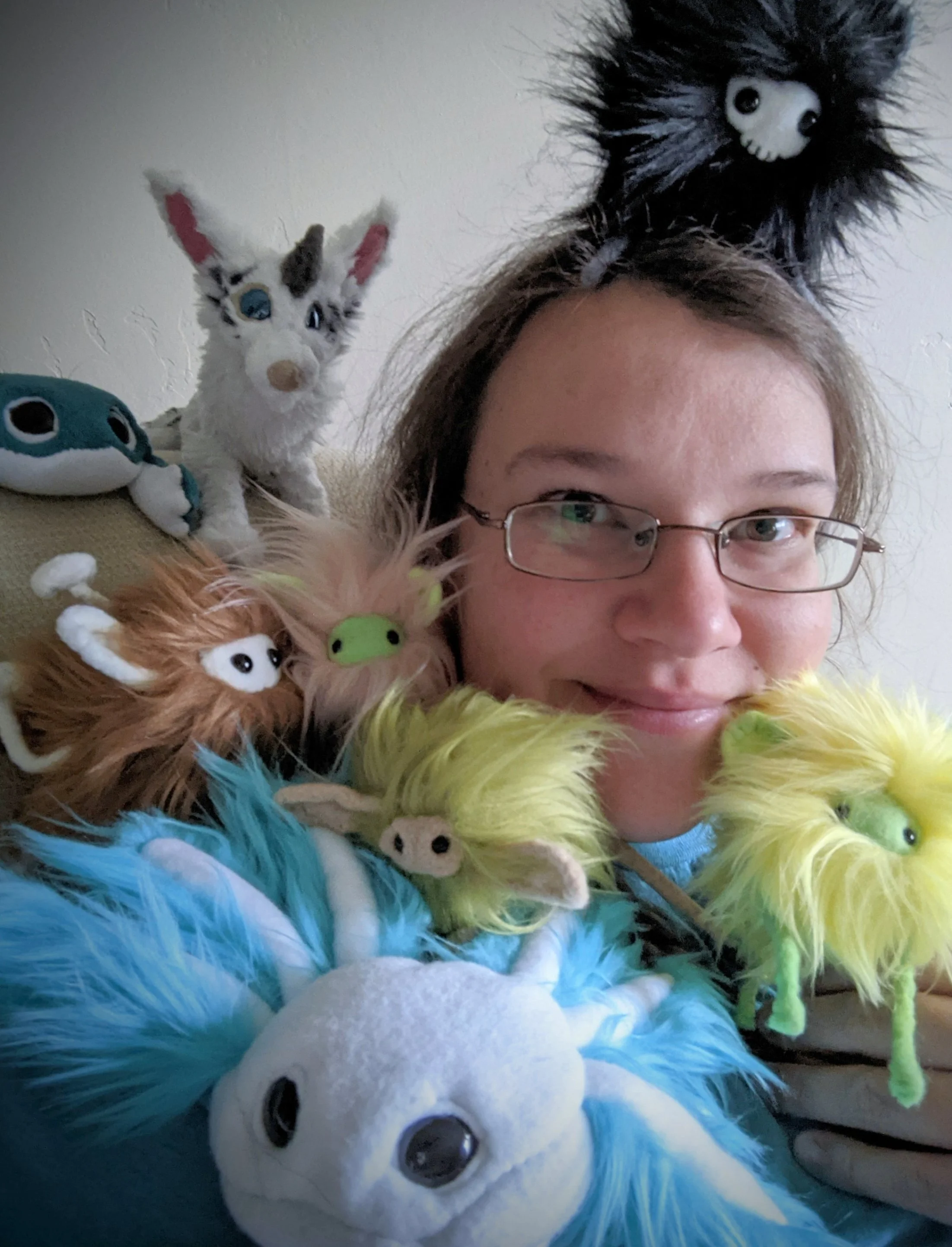 The artist smiles, surrounded by some of her plush creations.